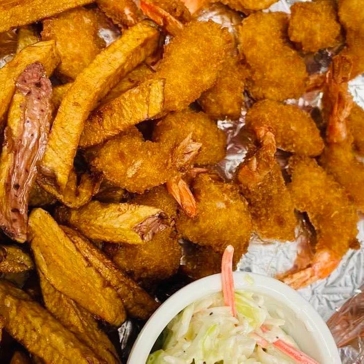 Golden fried chicken strips and crispy bites on foil, with a small cup of coleslaw.