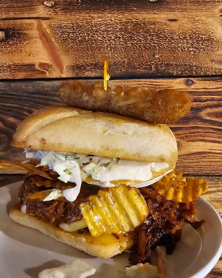 Two sandwiches with crinkle-cut chips on a plate, with a pickle on top.