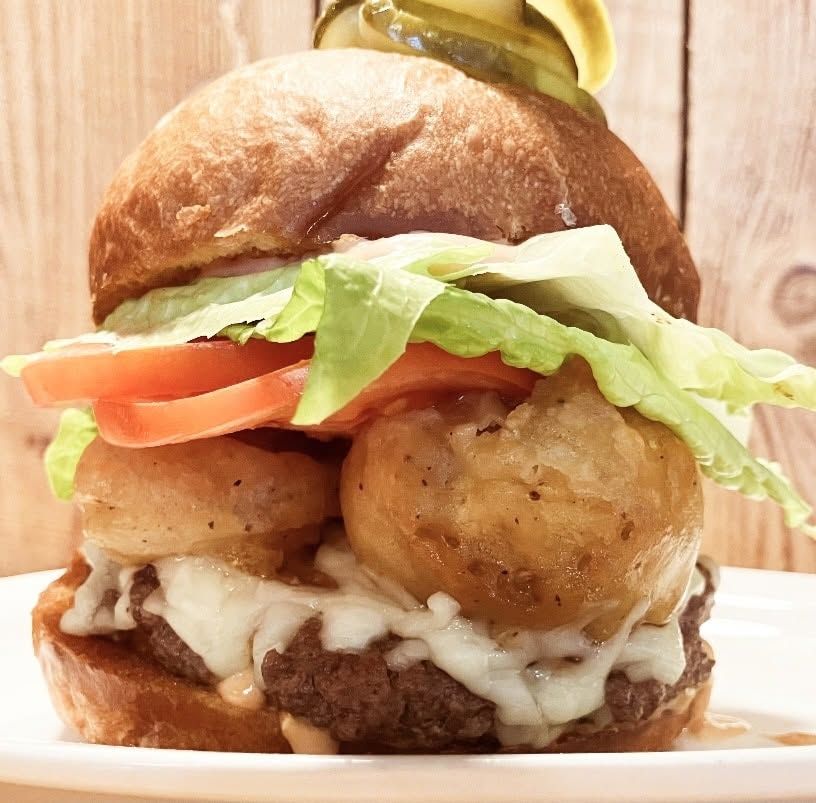 Double cheeseburger with lettuce, tomato, pickles, and sauce on a plate