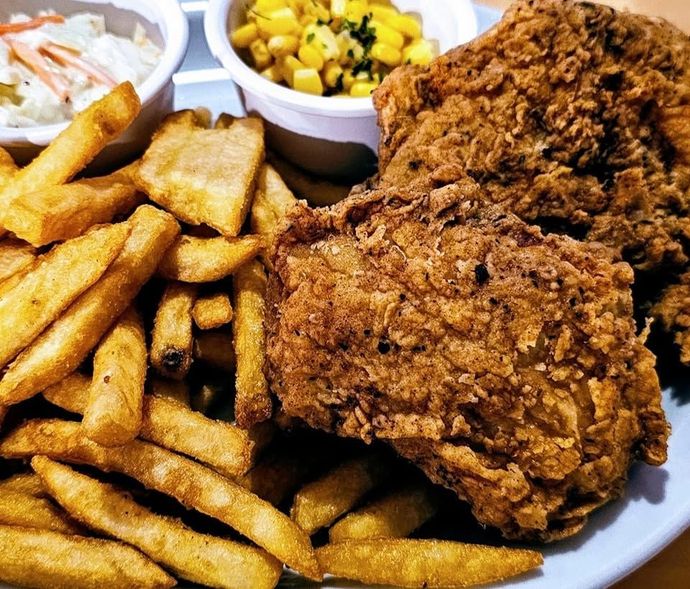 Fried chicken, thick-cut fries, and sides on a white plate