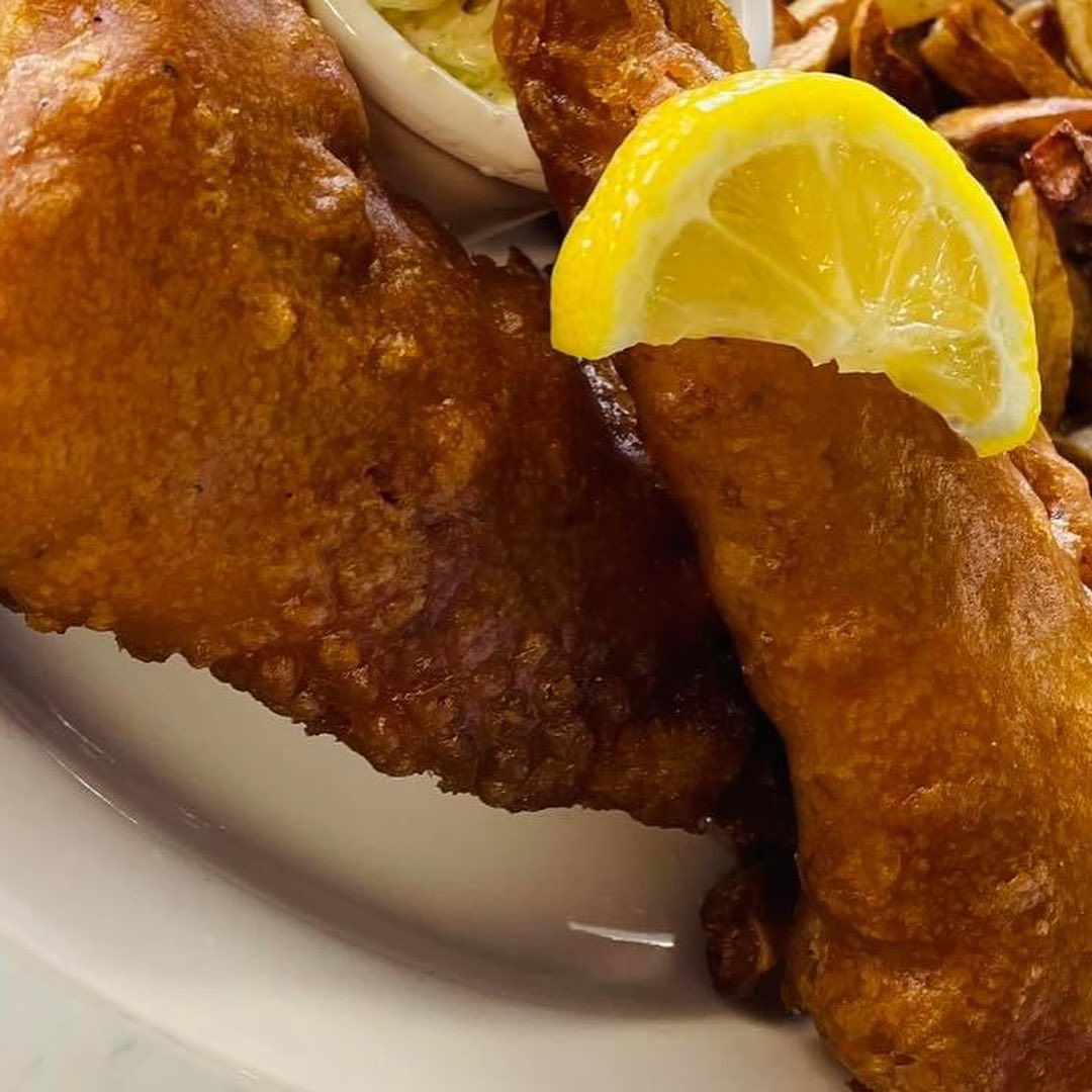 Close-up of fried fish on a plate with a lemon wedge on top