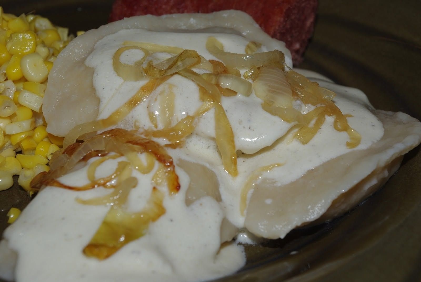 Plate of enchiladas topped with sour cream and fried onion, with corn on the side