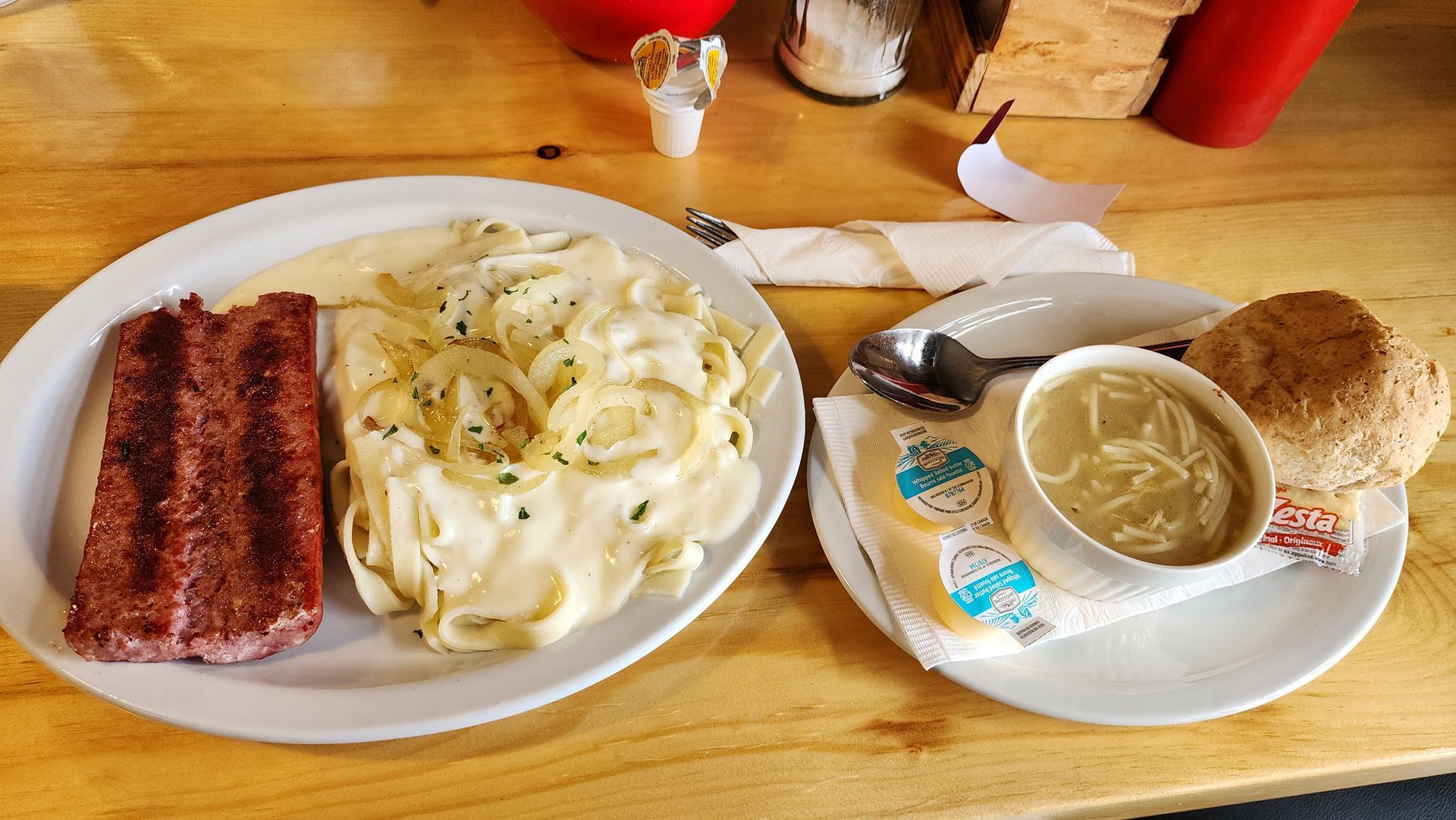 Breakfast tray with bacon, eggs, soup, and a biscuit on a wooden table