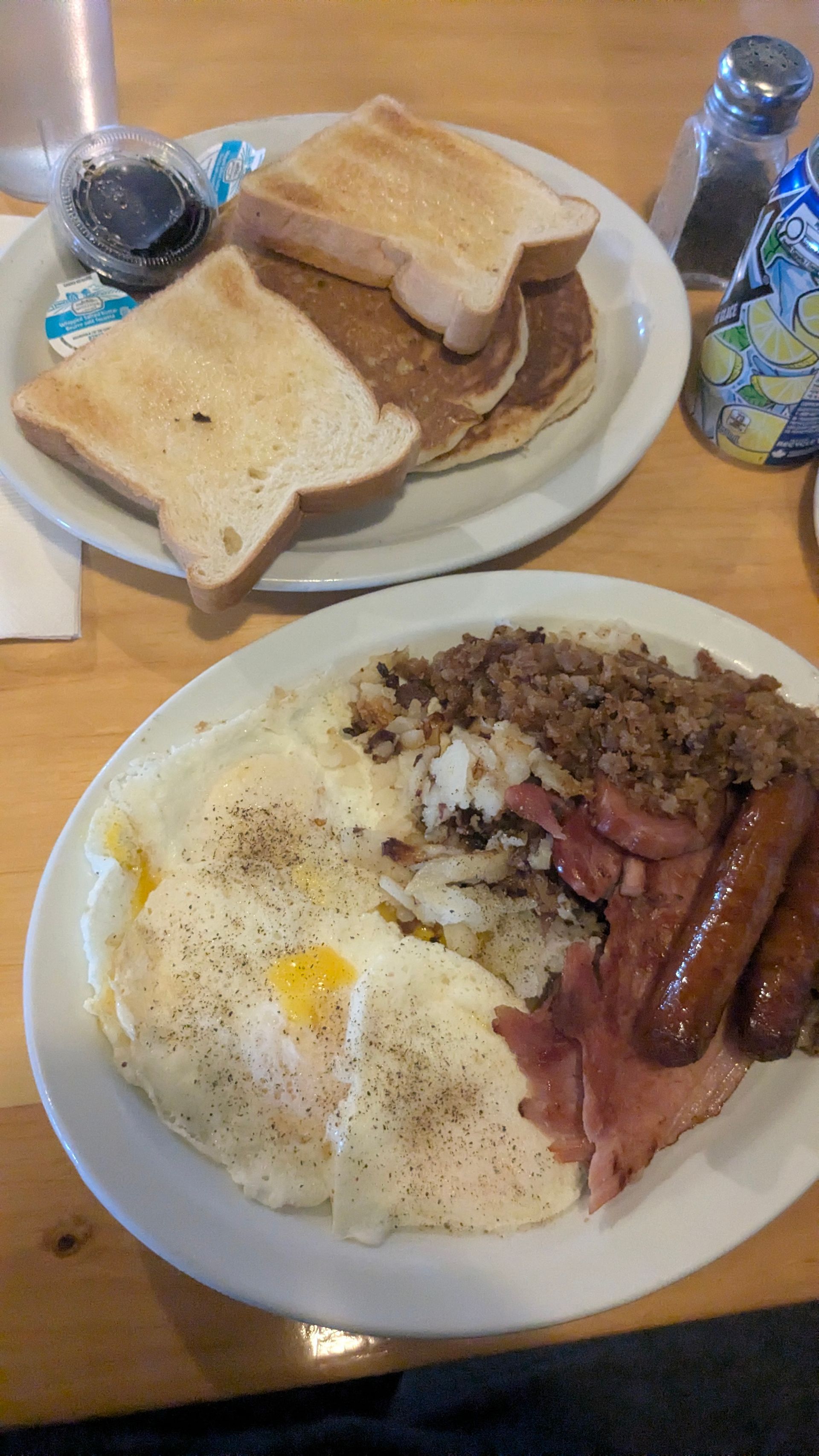 Breakfast plate with eggs, toast, sausage, bacon, and hash browns on a table
