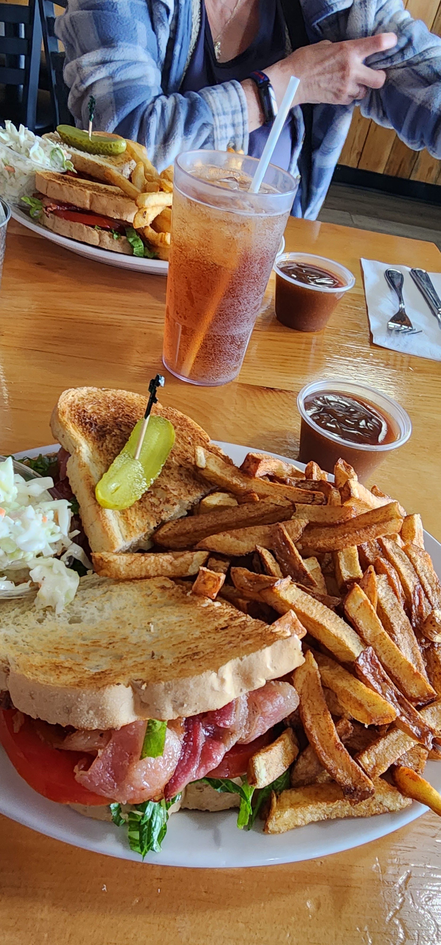 Restaurant table with a sandwich, fries, rice, and iced drinks on a wooden table