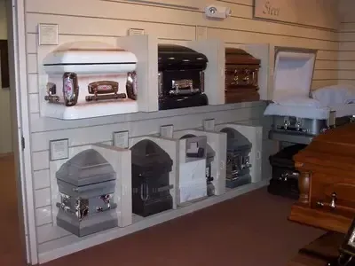 Caskets displayed in a funeral home, various colors and styles on shelves, for selection.