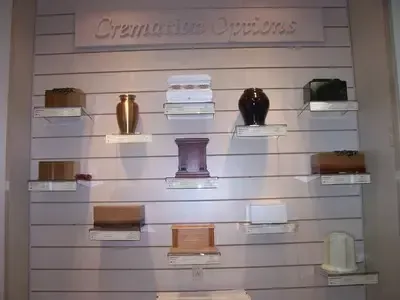 Display of cremation urn options on a wall, various colors, shapes, and sizes.