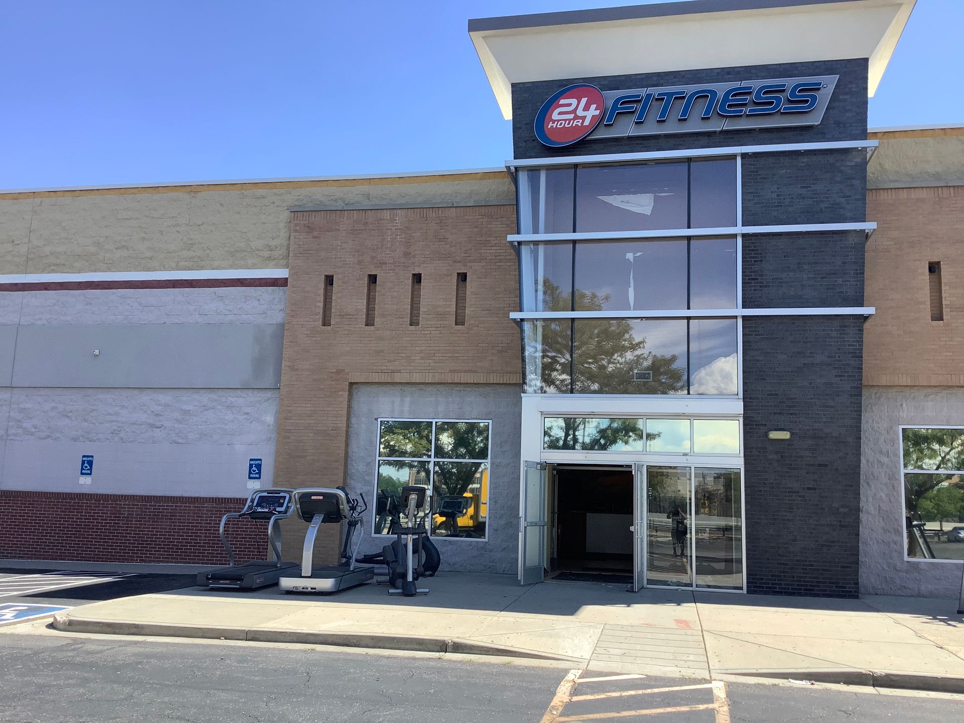 Storefront entrance with glass doors, tan brick facade, and sign above the awning