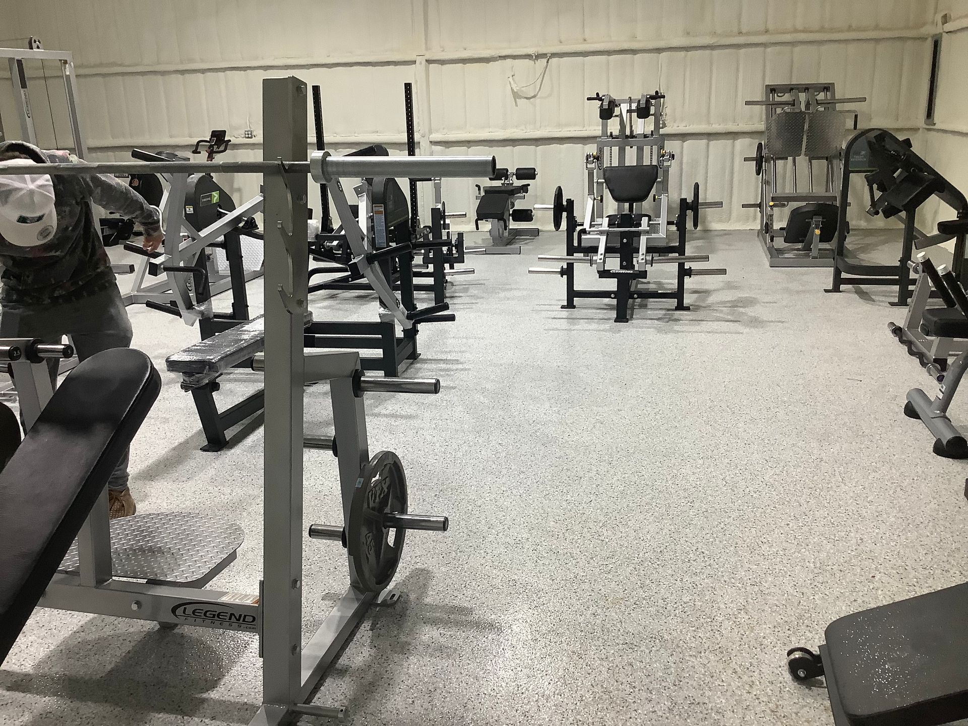 Gym room with weight machines, benches, and exercise equipment on a speckled floor