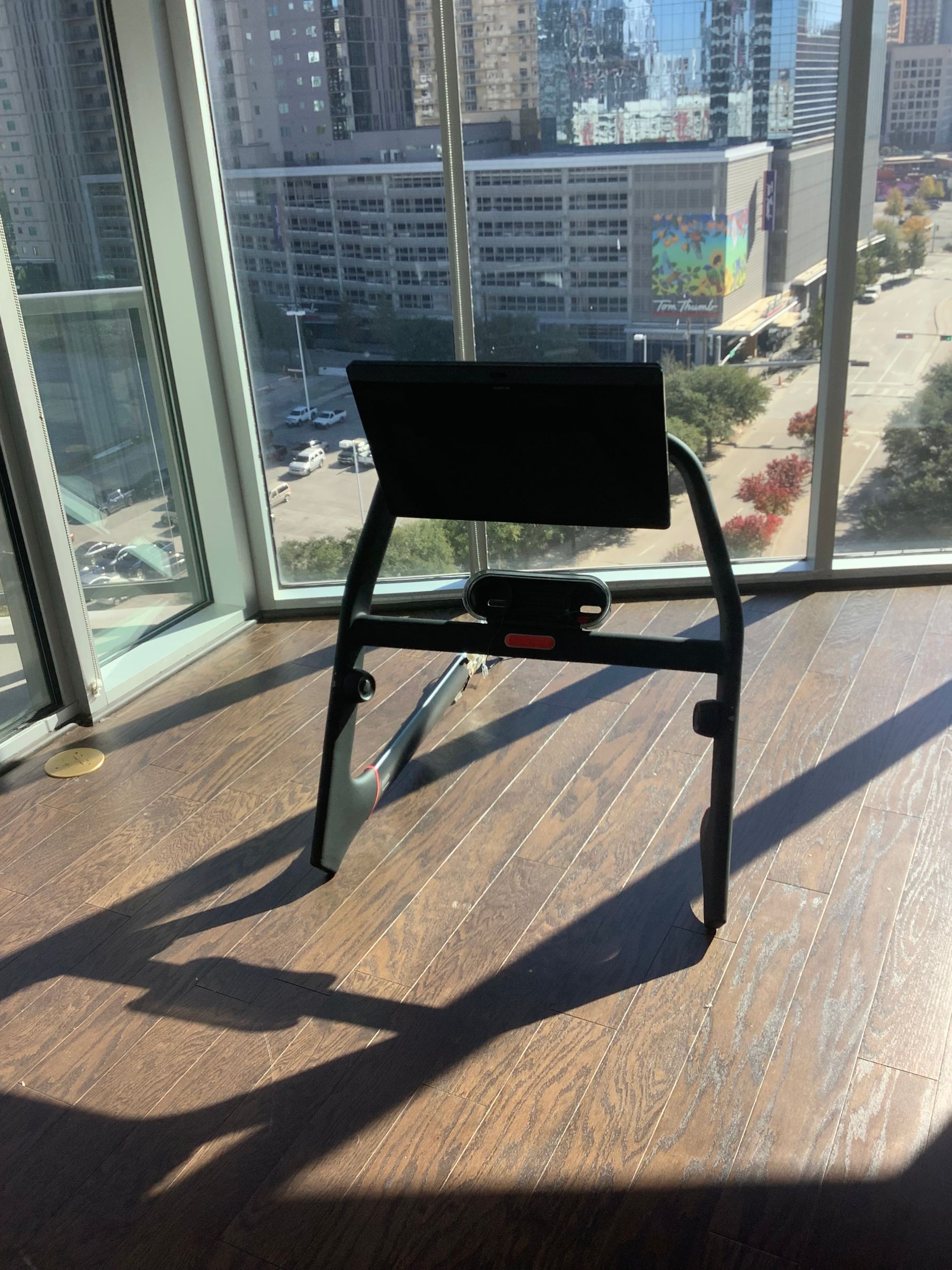 Black chair by floor-to-ceiling windows in a sunlit high-rise room