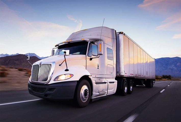 a white semi truck is driving down a highway