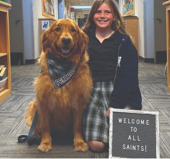 Girl kneeling with golden retriever dog wearing a bandana that says