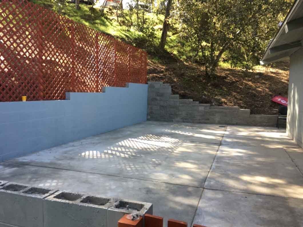 A concrete patio with a fence and stairs in the background