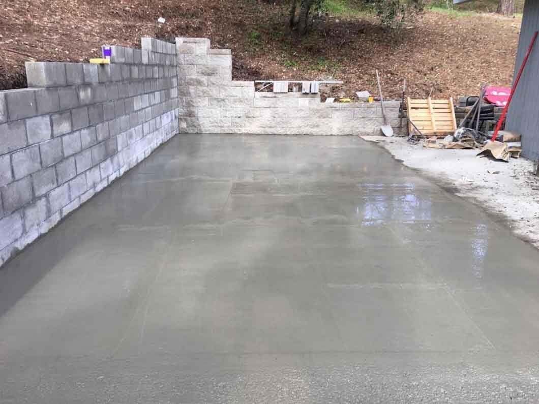 A concrete driveway is being built next to a brick wall.