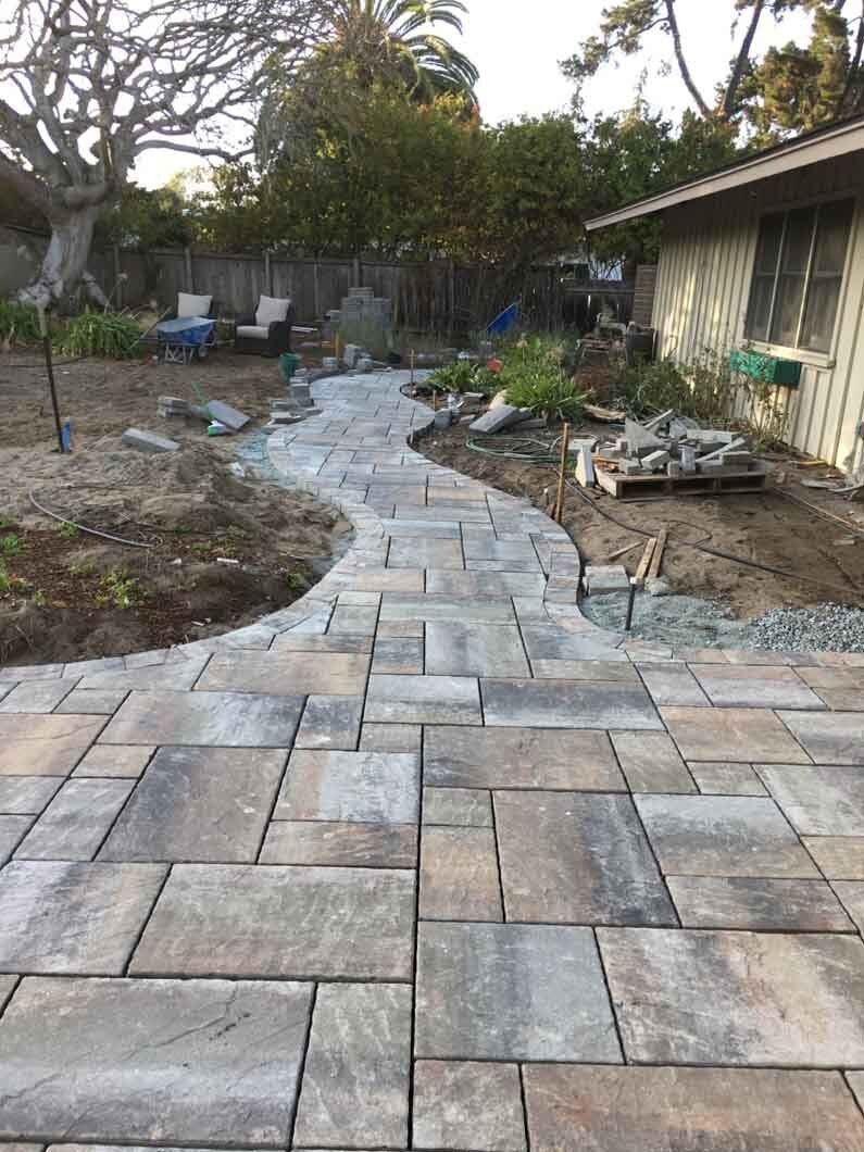 A walkway is being built in the backyard of a house.