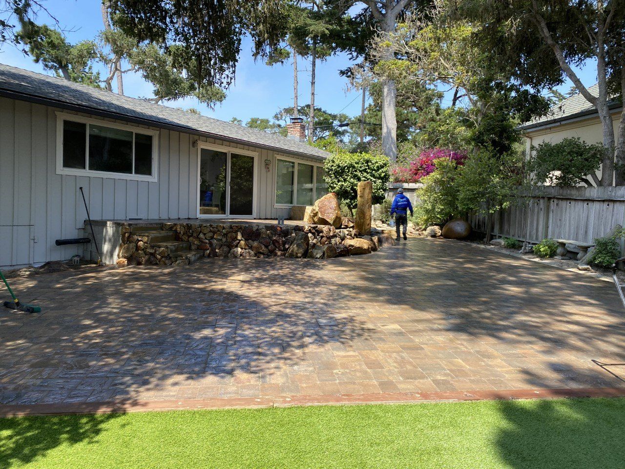 A man is cleaning a patio in front of a house.