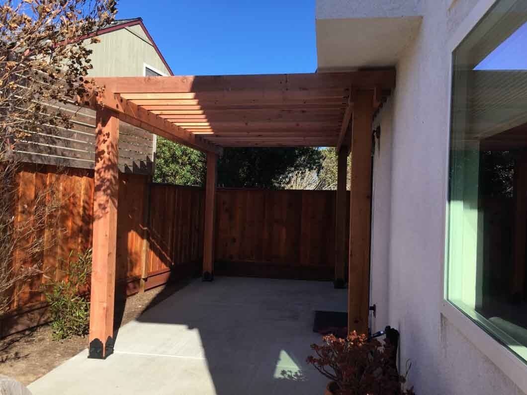 There is a pergola in the backyard of a house.