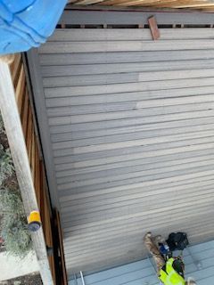 A man in a yellow vest is standing on a wooden deck.
