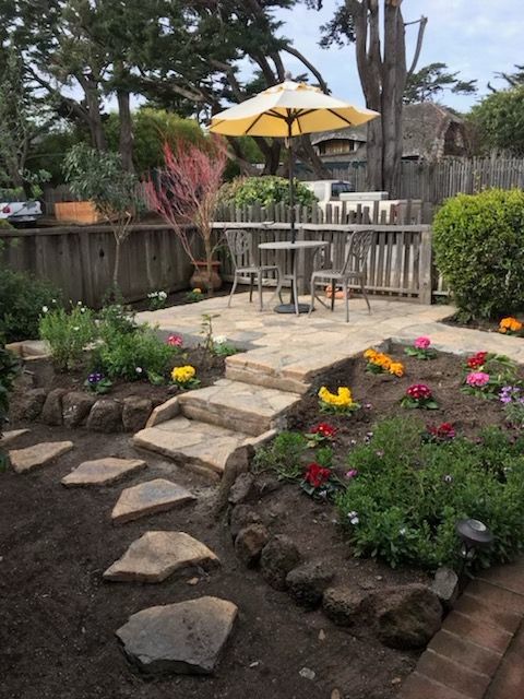 A garden with a table and chairs and a yellow umbrella