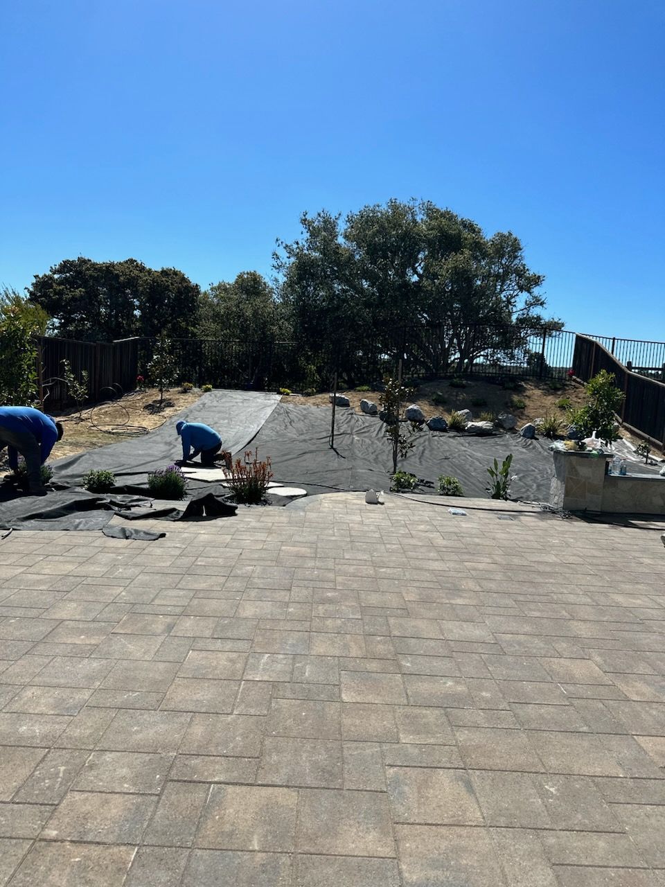 Two men are working on a patio with a blue sky in the background