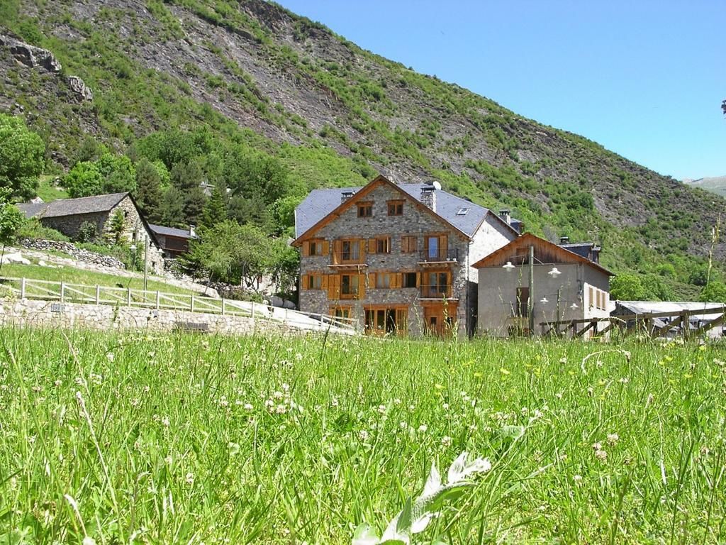 Cabanyes de fusta a la muntanya, al costat d’un prat verd sota un cel blau i clar