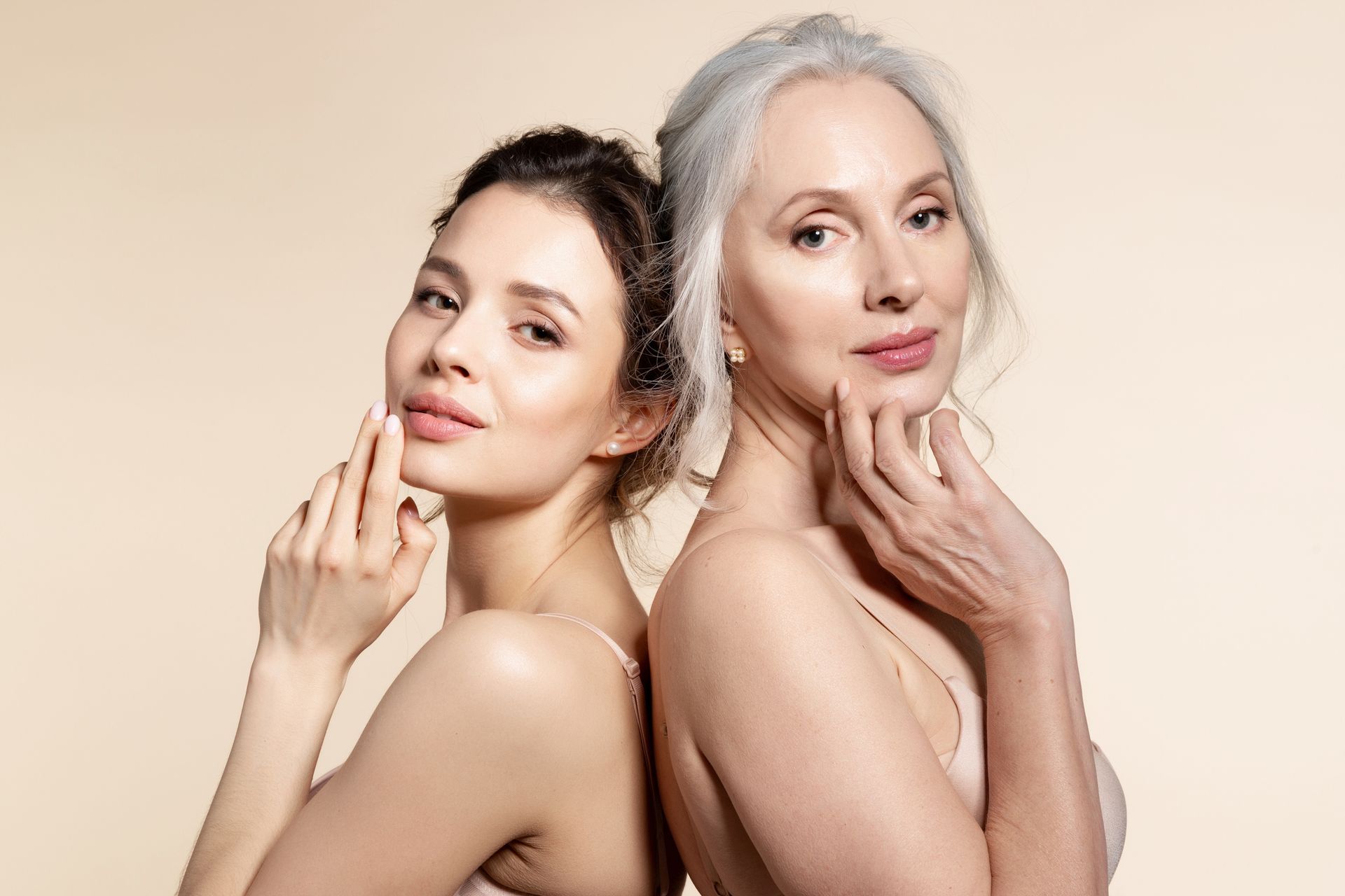 a young woman and an older woman are standing back to back .