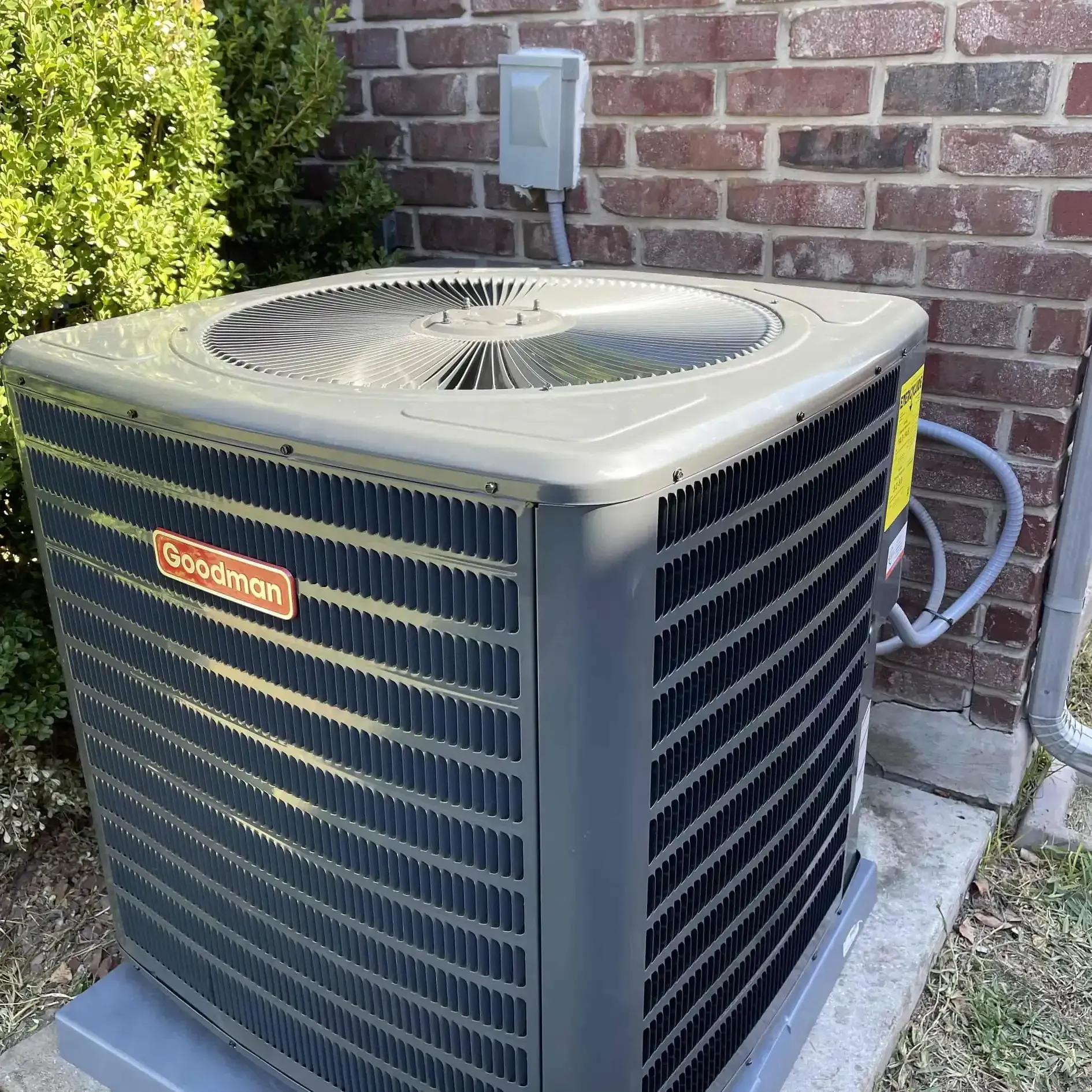 Goodman air conditioning unit outside a brick building.