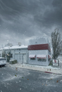 A snowy street scene with a small building, a tree, and a parked vehicle.