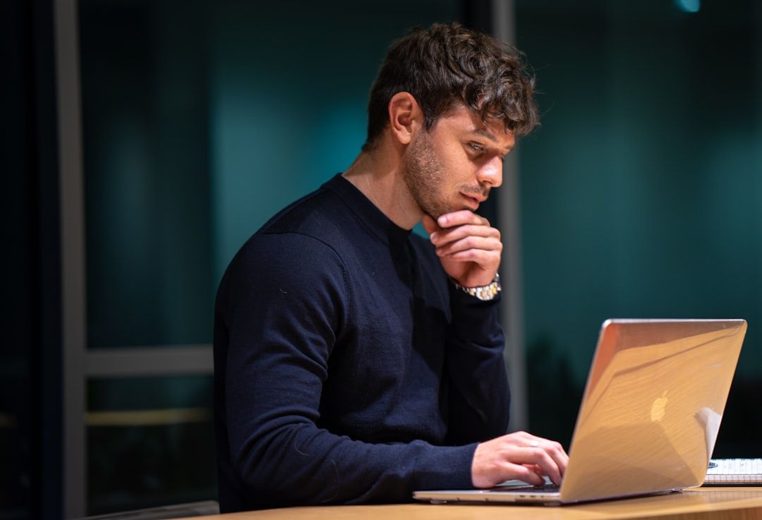 Man thinking while working on laptop for marketing automation software for small business
