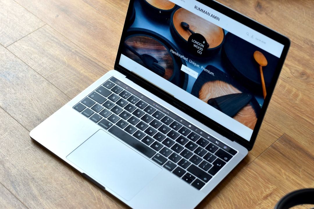 Laptop displaying website pages on a wooden floor.
