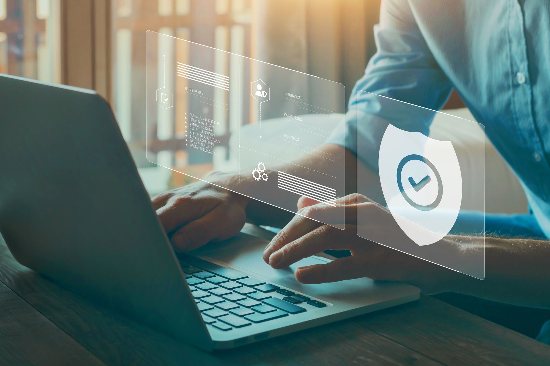 Person typing on laptop with digital security icons and shield overlay.