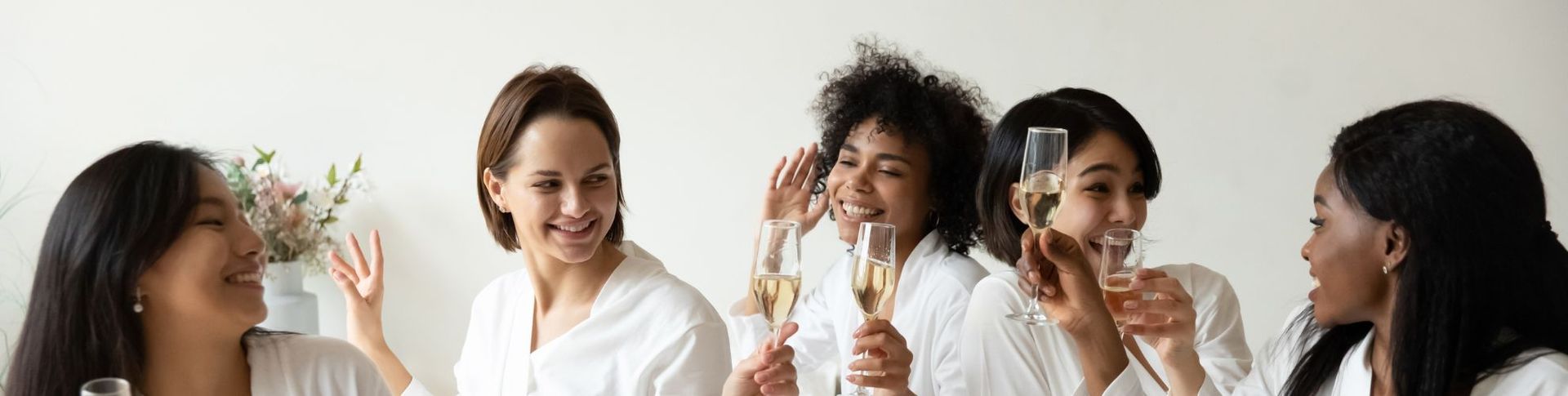 Five people laughing and clinking champagne glasses at a party table