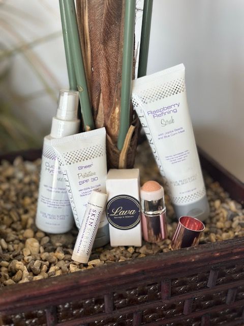 Assorted skincare products and makeup brushes arranged on a decorative tray with pebbles and plant stems.