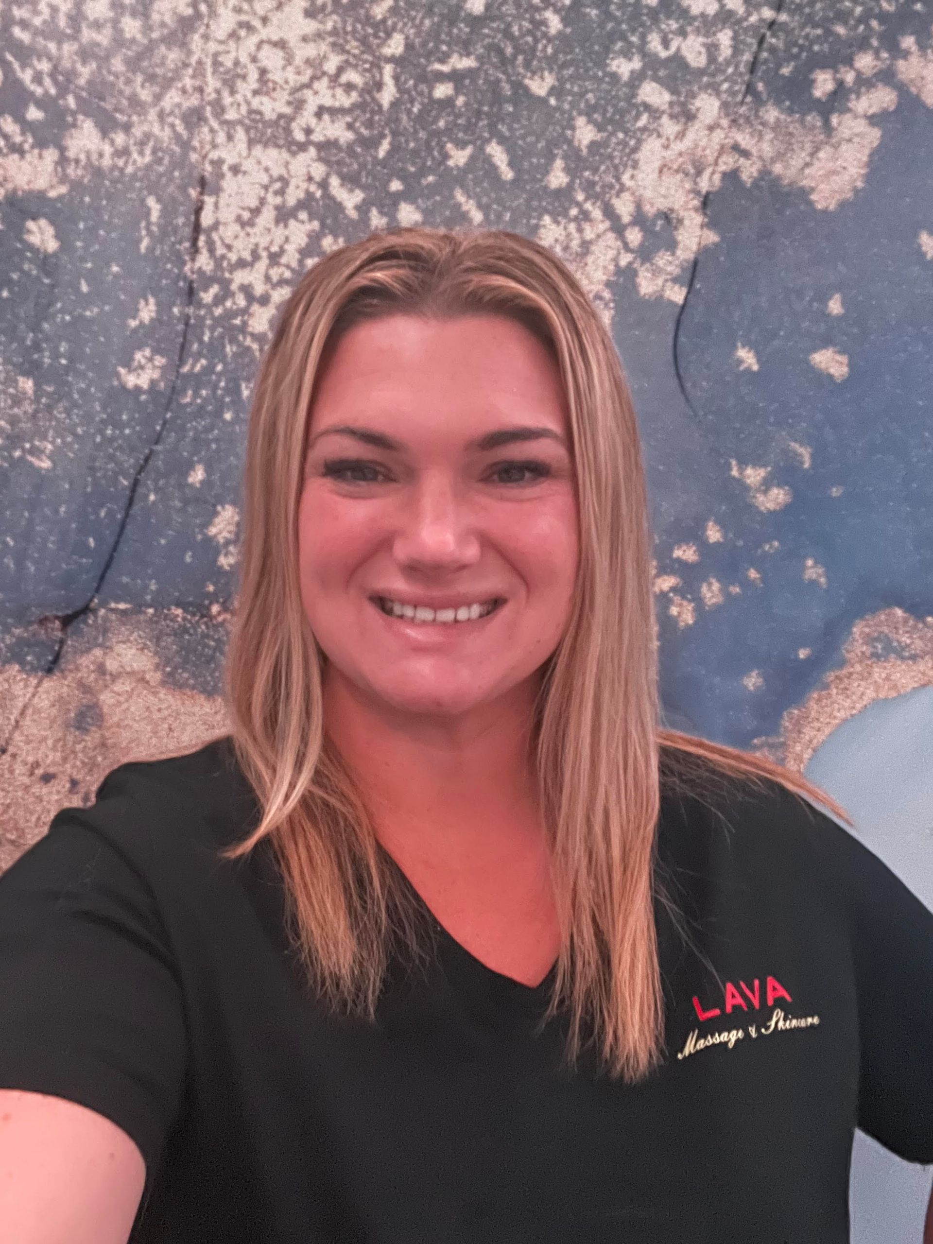 Woman smiling in a black shirt against a blue-and-white textured wall