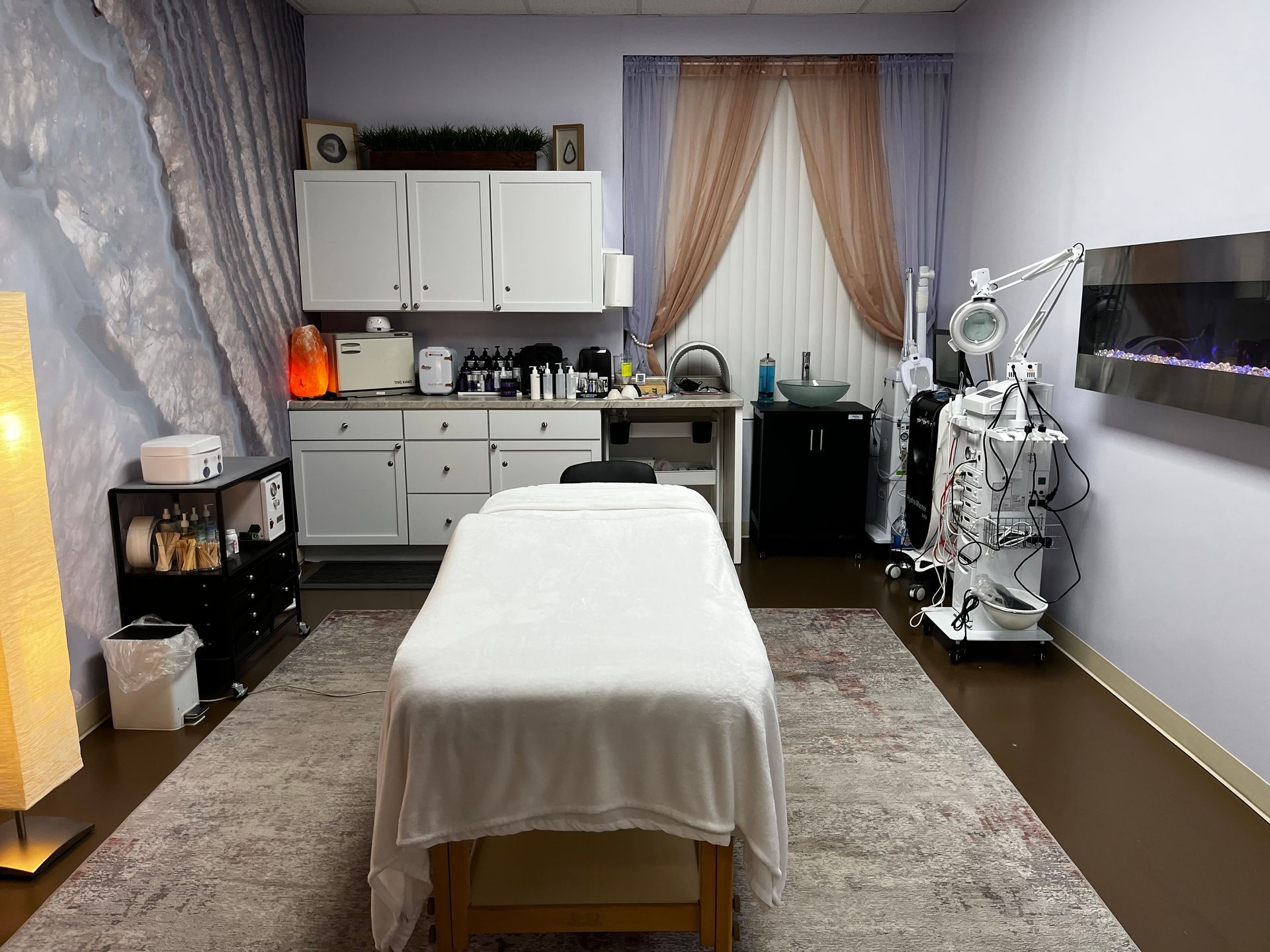 Massage treatment room with bed, cabinets, and a robotic therapy device by the wall