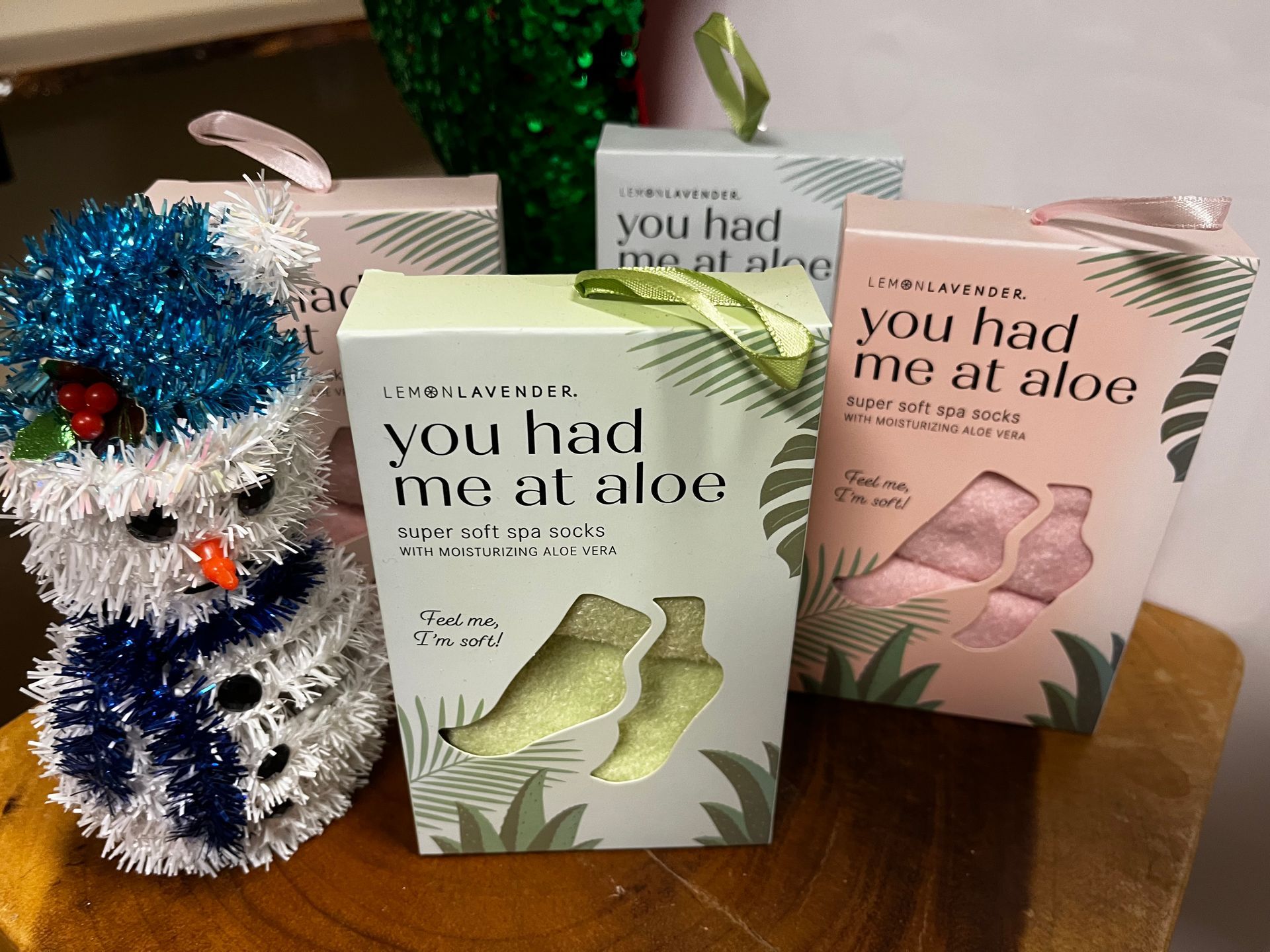 Aloe-themed gift bags and a fuzzy white-and-blue ornament on a table.