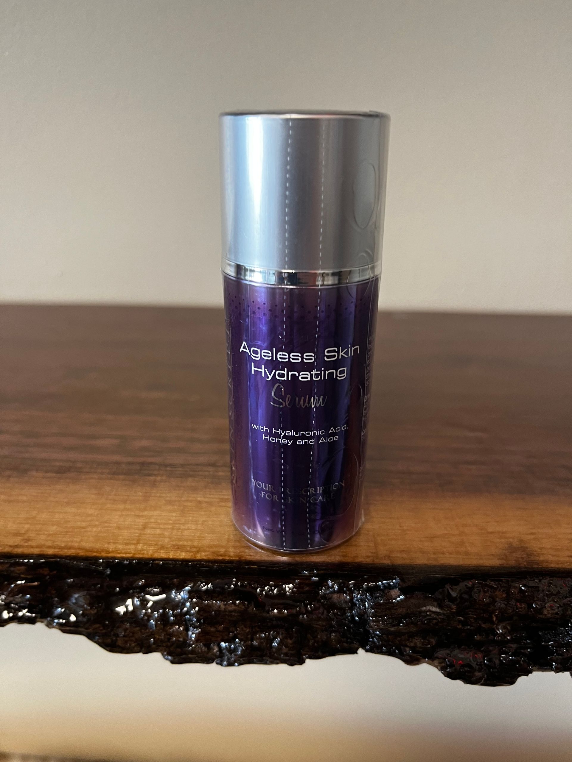 Purple cosmetic tube with silver cap standing on a wooden surface