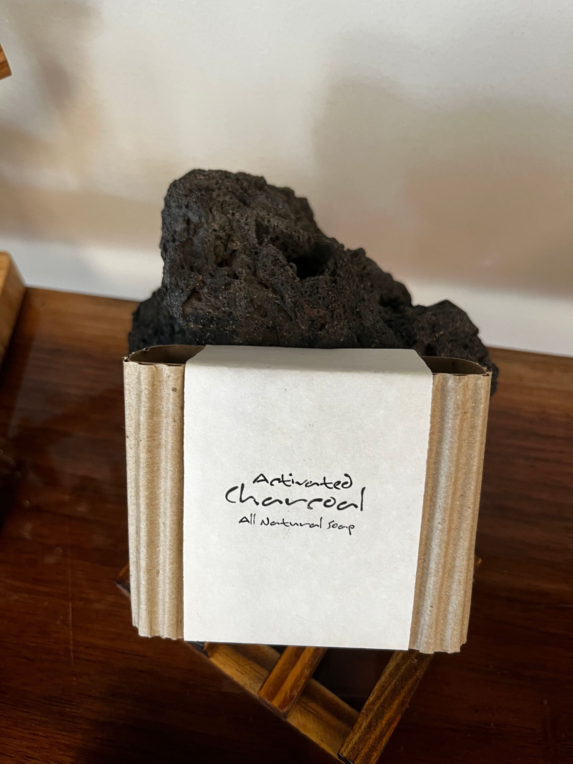 Black charcoal chunks in a small white-labeled box on a wooden surface.