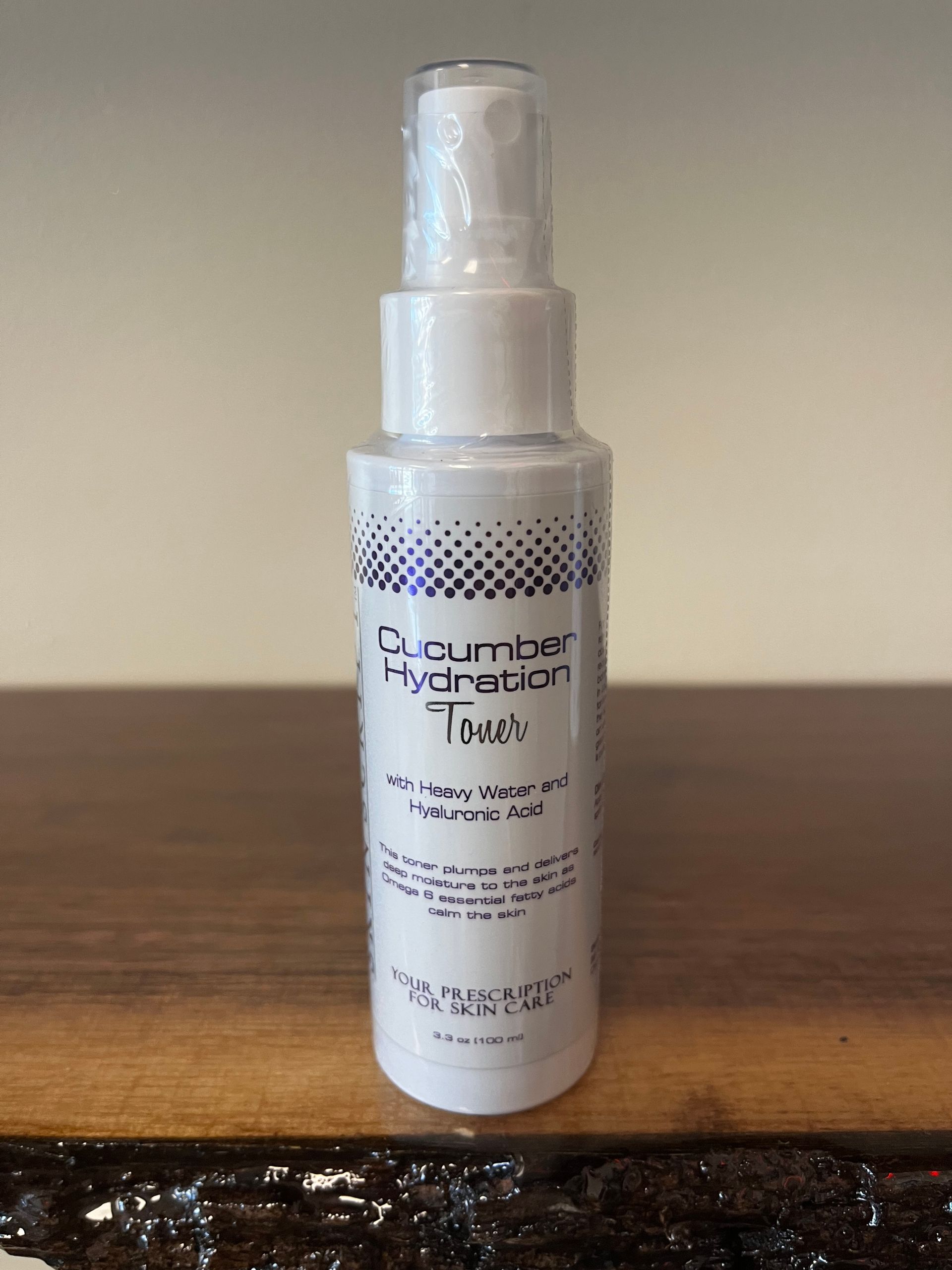 Clear pump bottle of “Cucumber Hydration Toner” on a wooden table