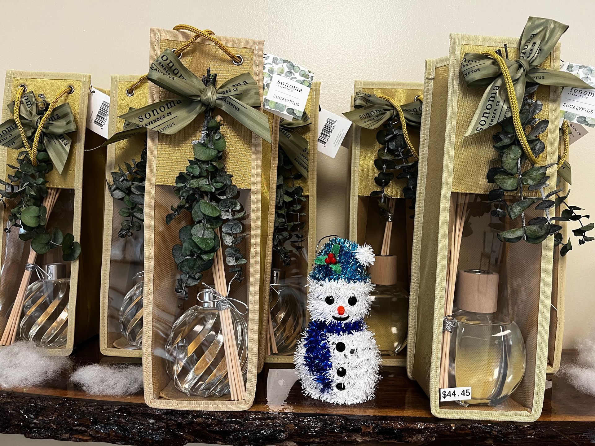 Four wrapped holiday gift boxes with pinecones, ribbon, and a small snowman decoration