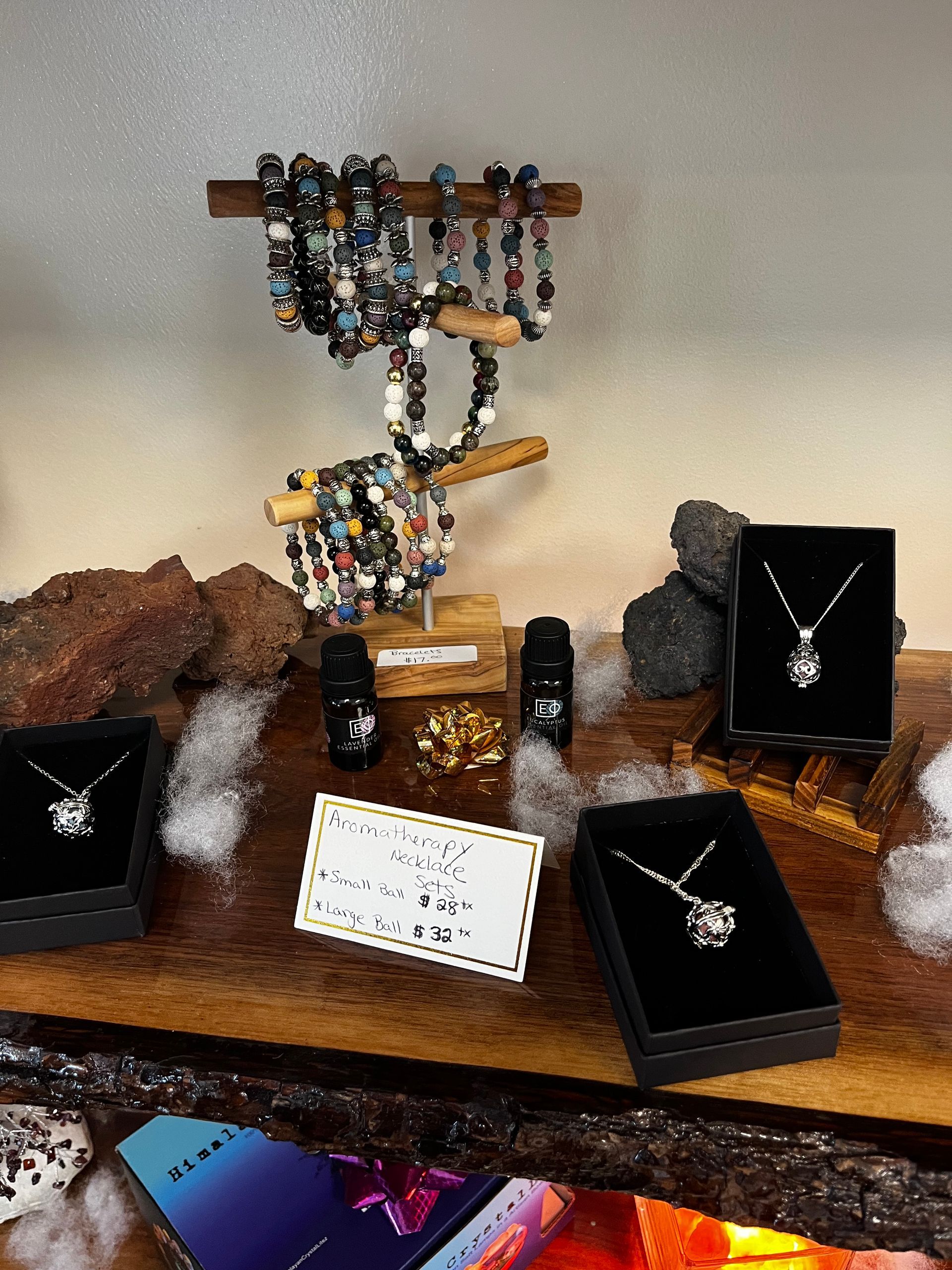 Jewelry display with beaded bracelets, silver necklaces, and black velvet gift boxes on a rustic shelf.