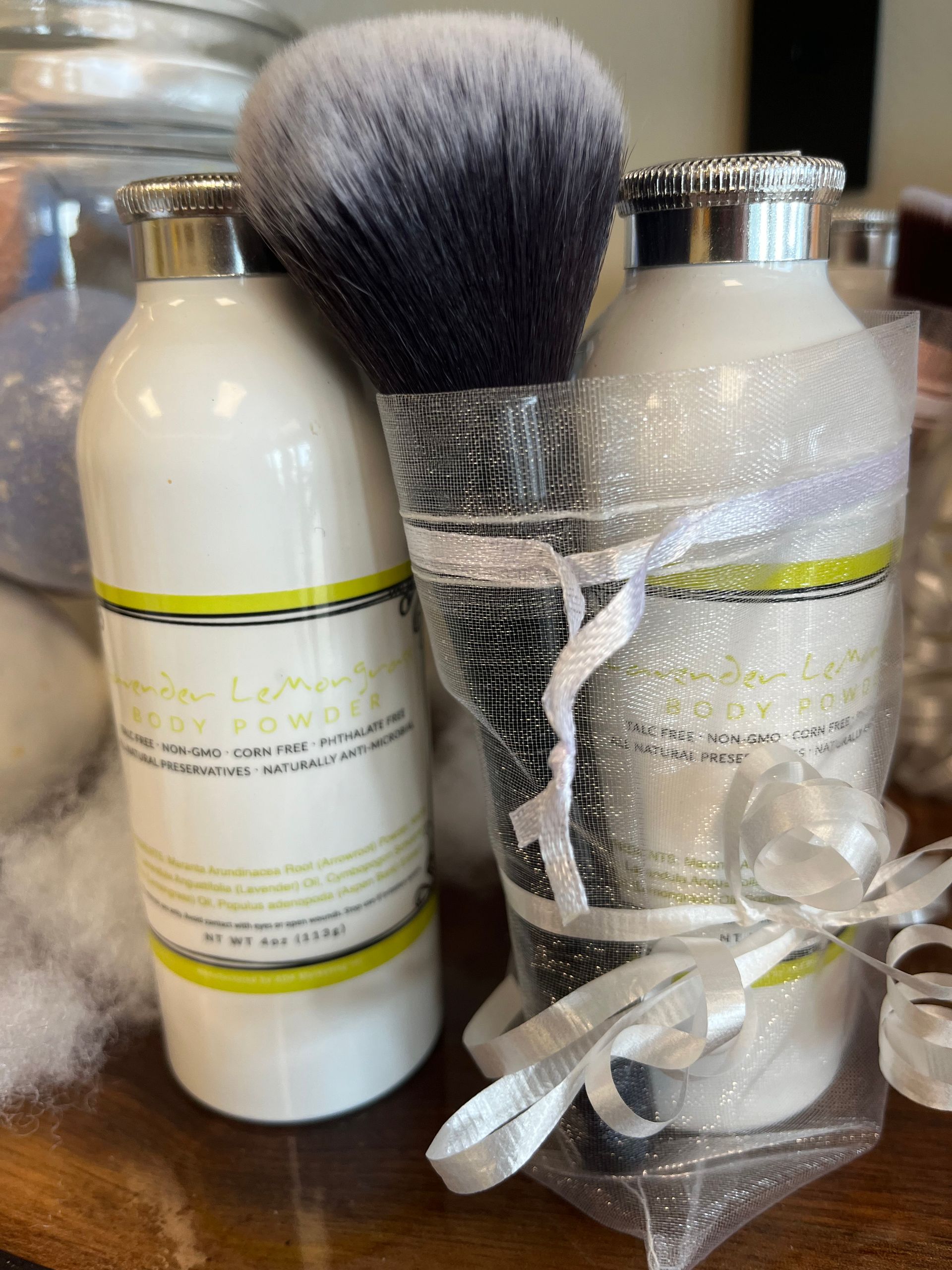 Gift set with a shaving brush and two cream bottles wrapped in clear plastic and tied with ribbon.