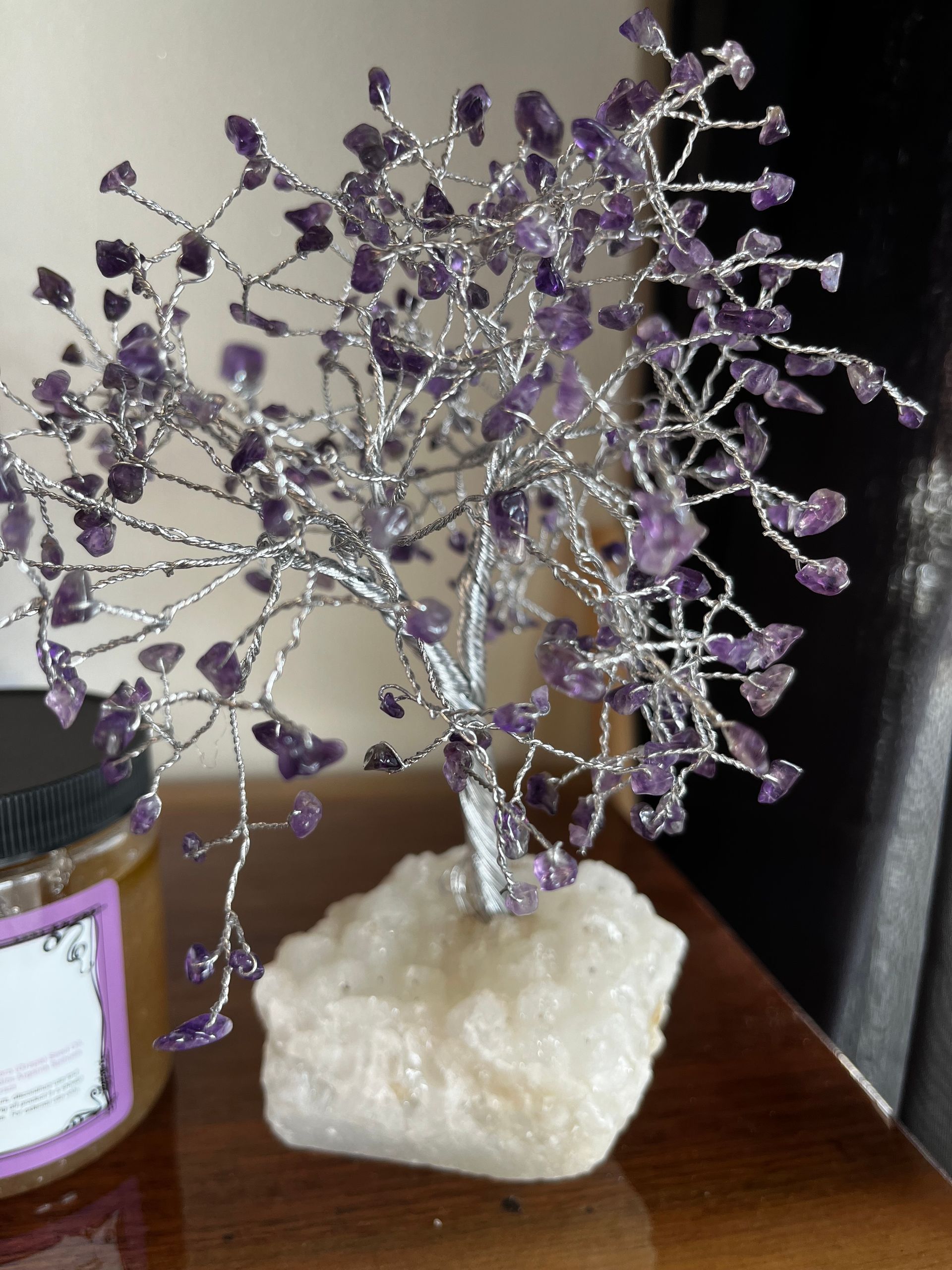 Purple gemstone wire tree on a white rock base sitting on a wooden surface.