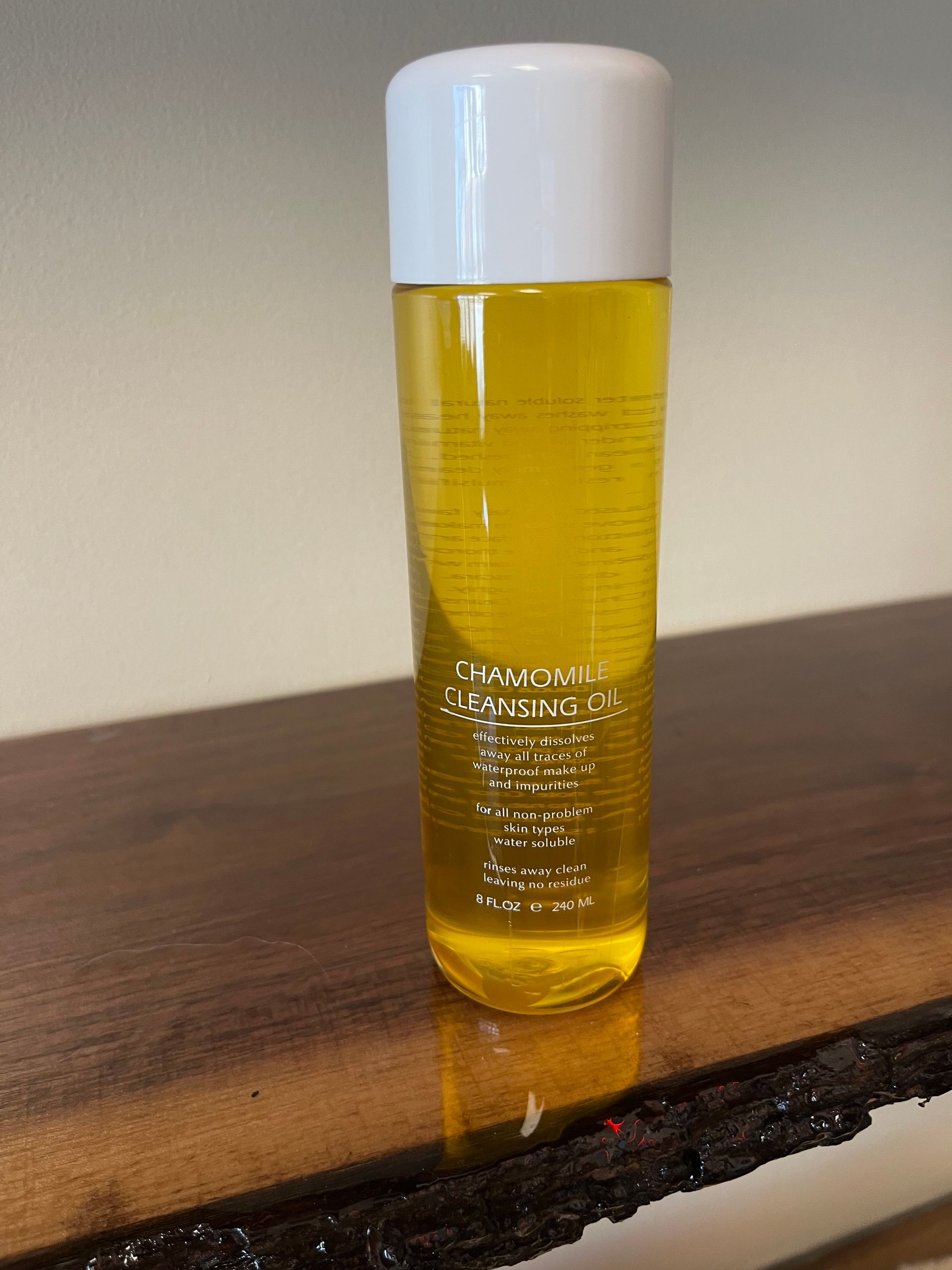 Yellow cosmetic bottle with a white cap standing on a wooden table.