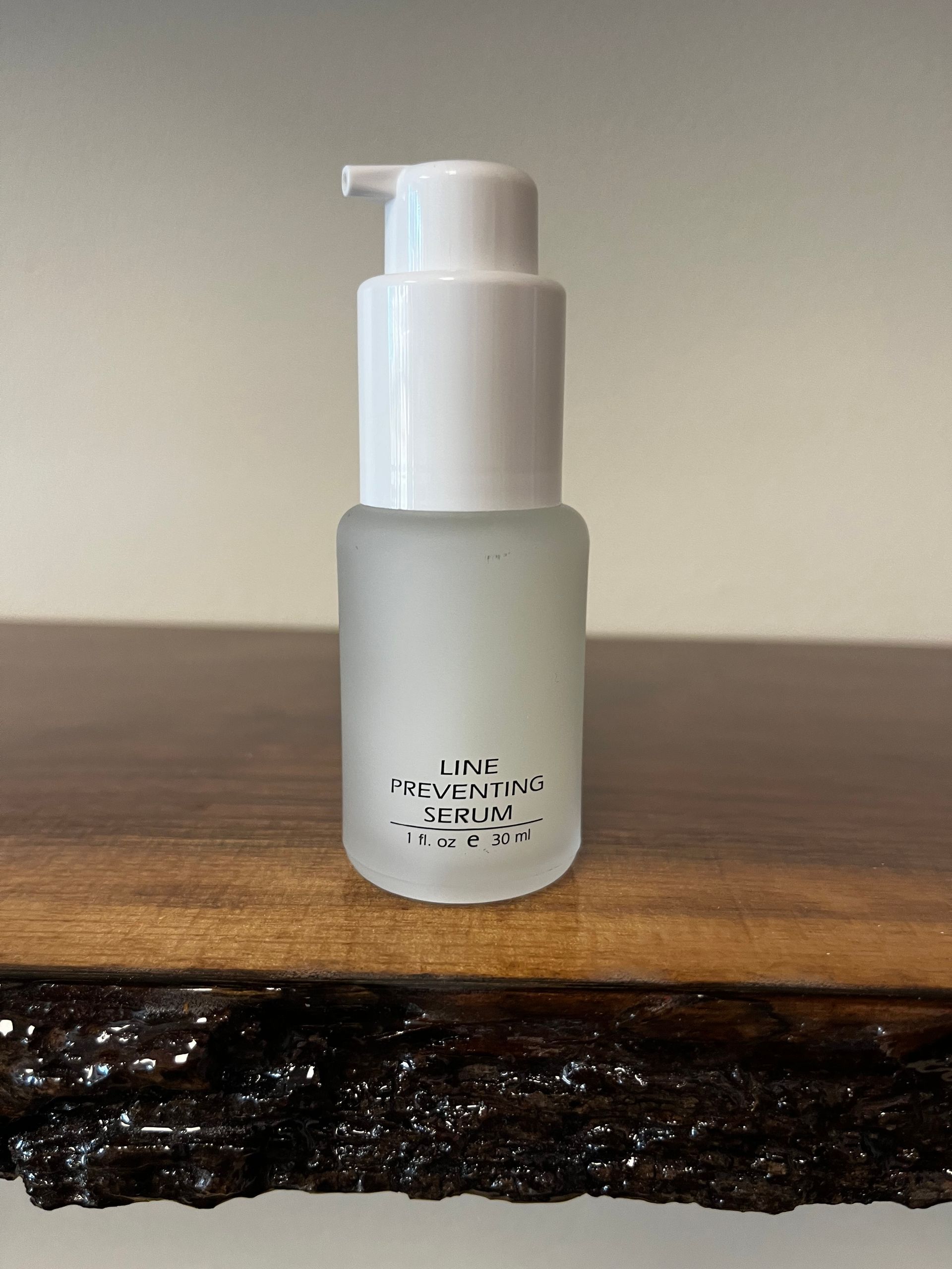 Small frosted pump bottle on a wooden surface against a plain wall.