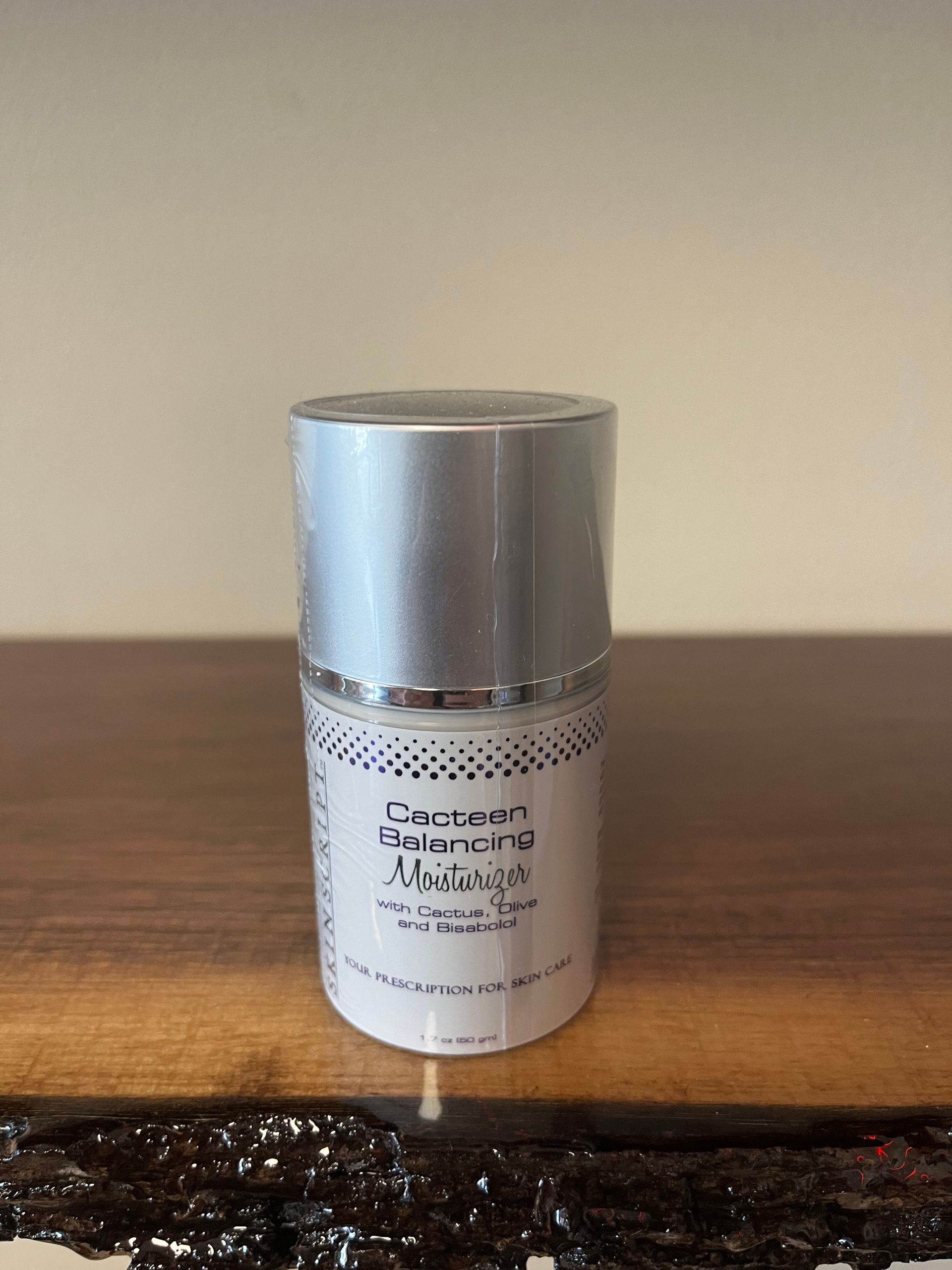 Silver-capped white cosmetic bottle on a wooden table against a beige wall