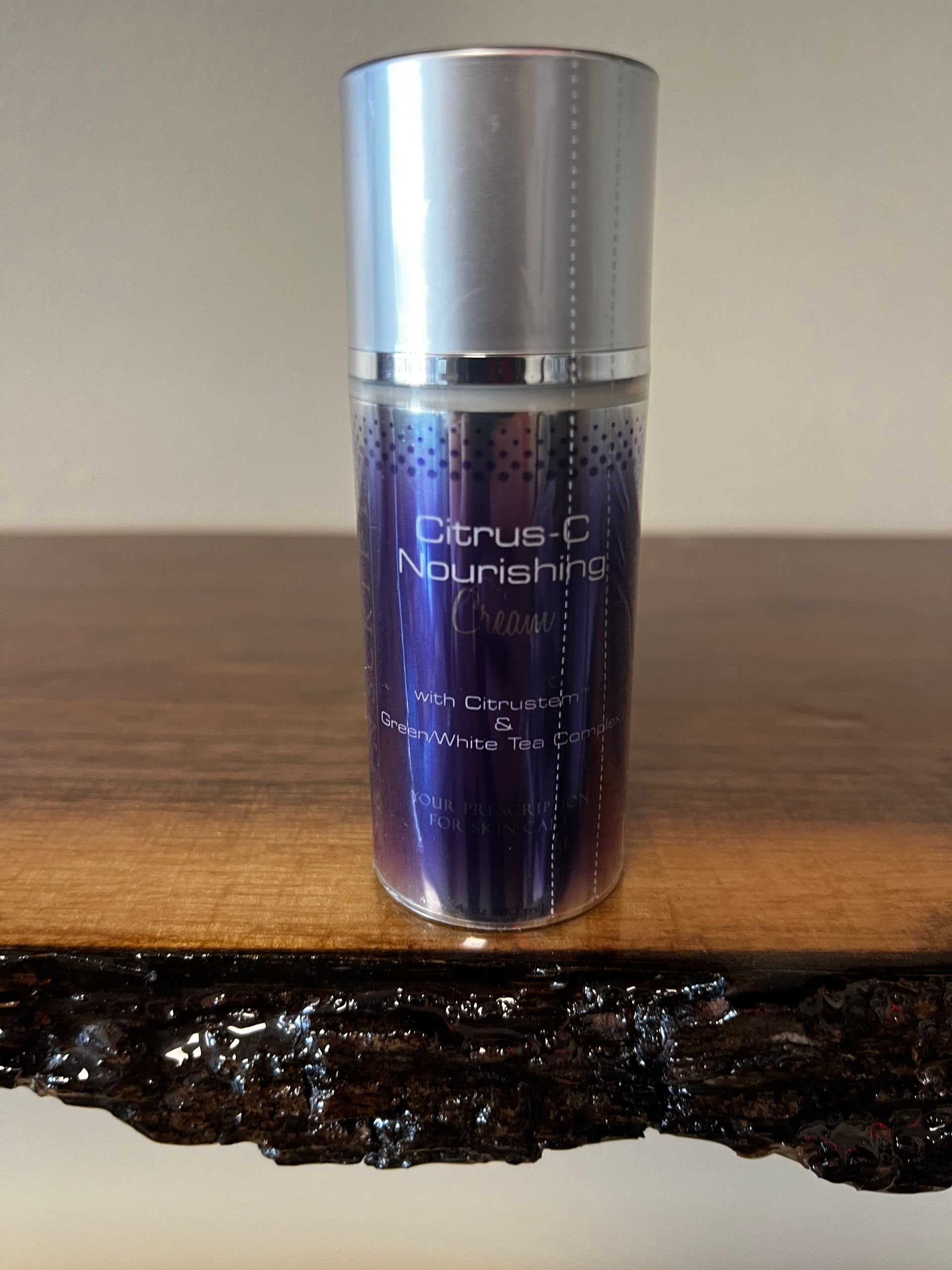 Purple Clinique moisturizer bottle with silver cap on a wooden surface