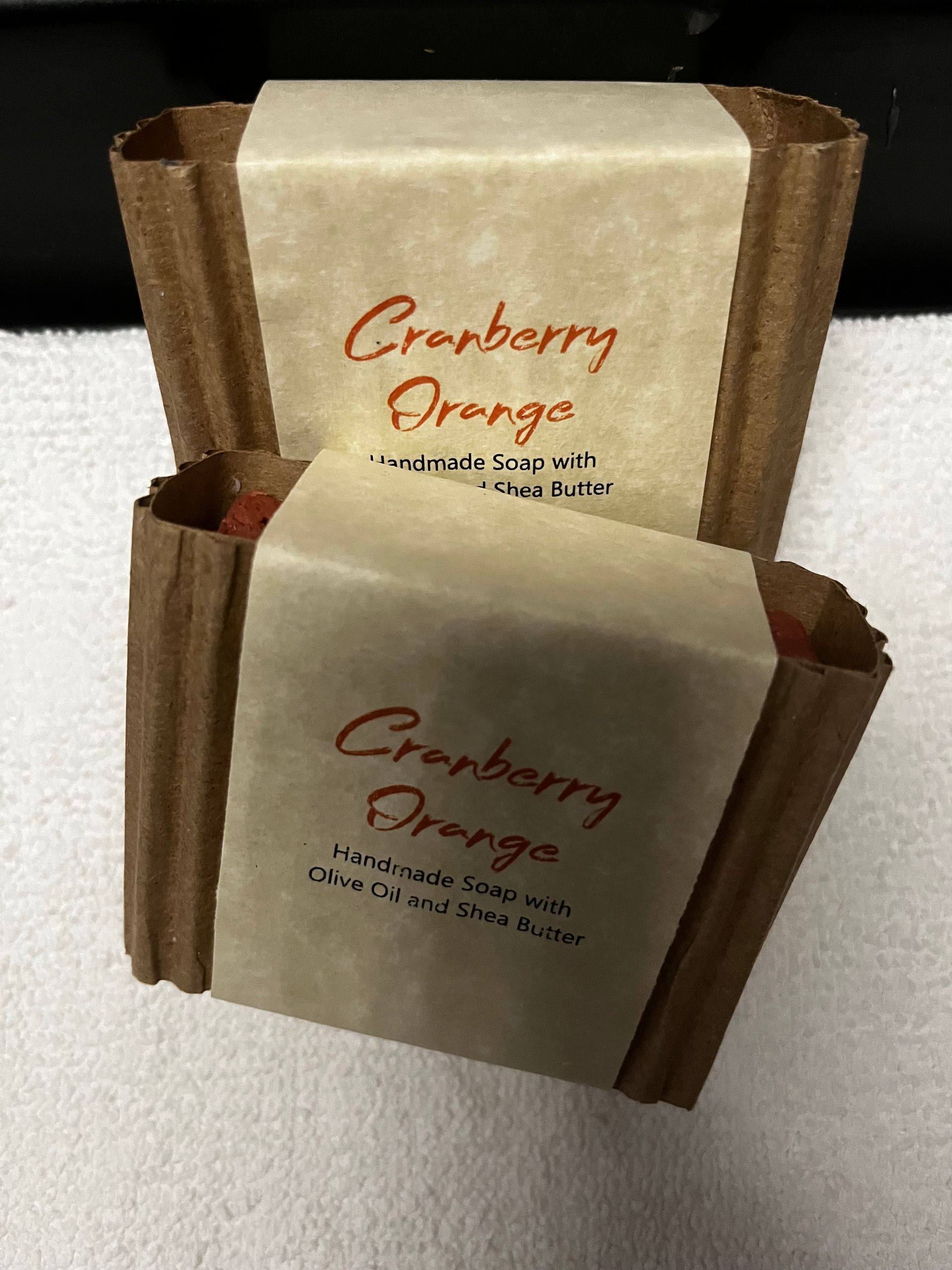 Two cranberry orange dessert bars in brown packaging with cream labels on a white surface
