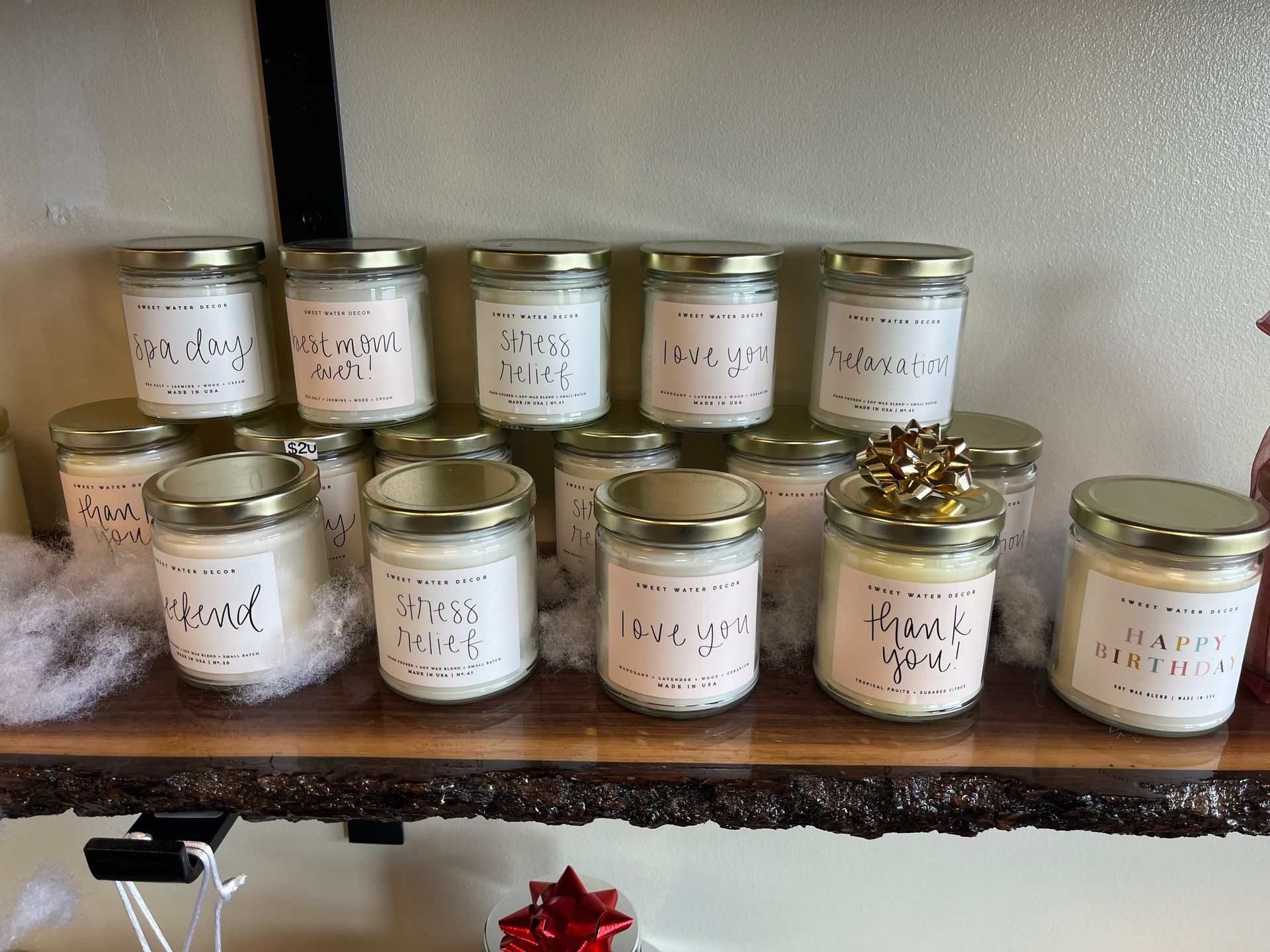 Two rows of labeled glass jars with gold lids on a rustic wooden shelf
