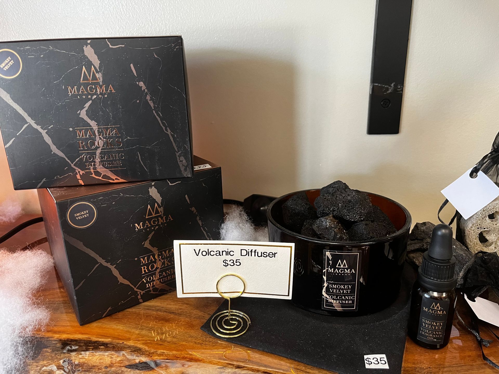 Black marble-pattern gift boxes and matching bath items arranged on a pink surface with a small sign.